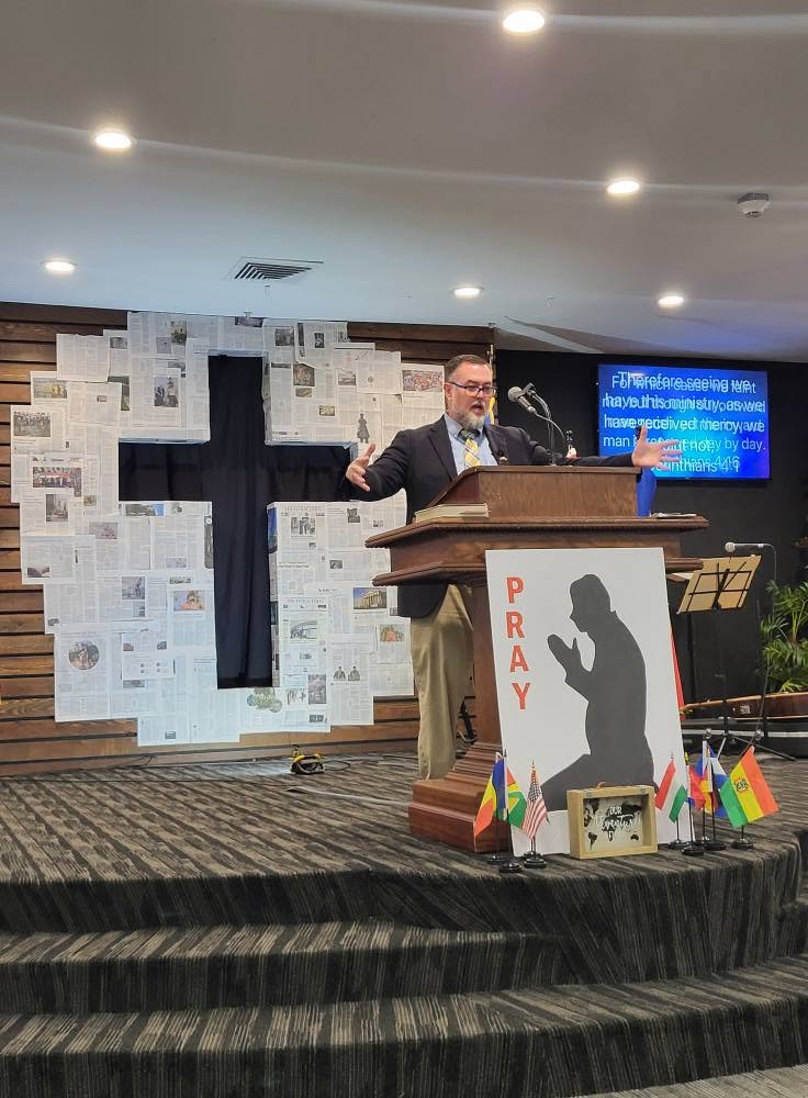 Pastor preaching from the pulpit with a cross behind him