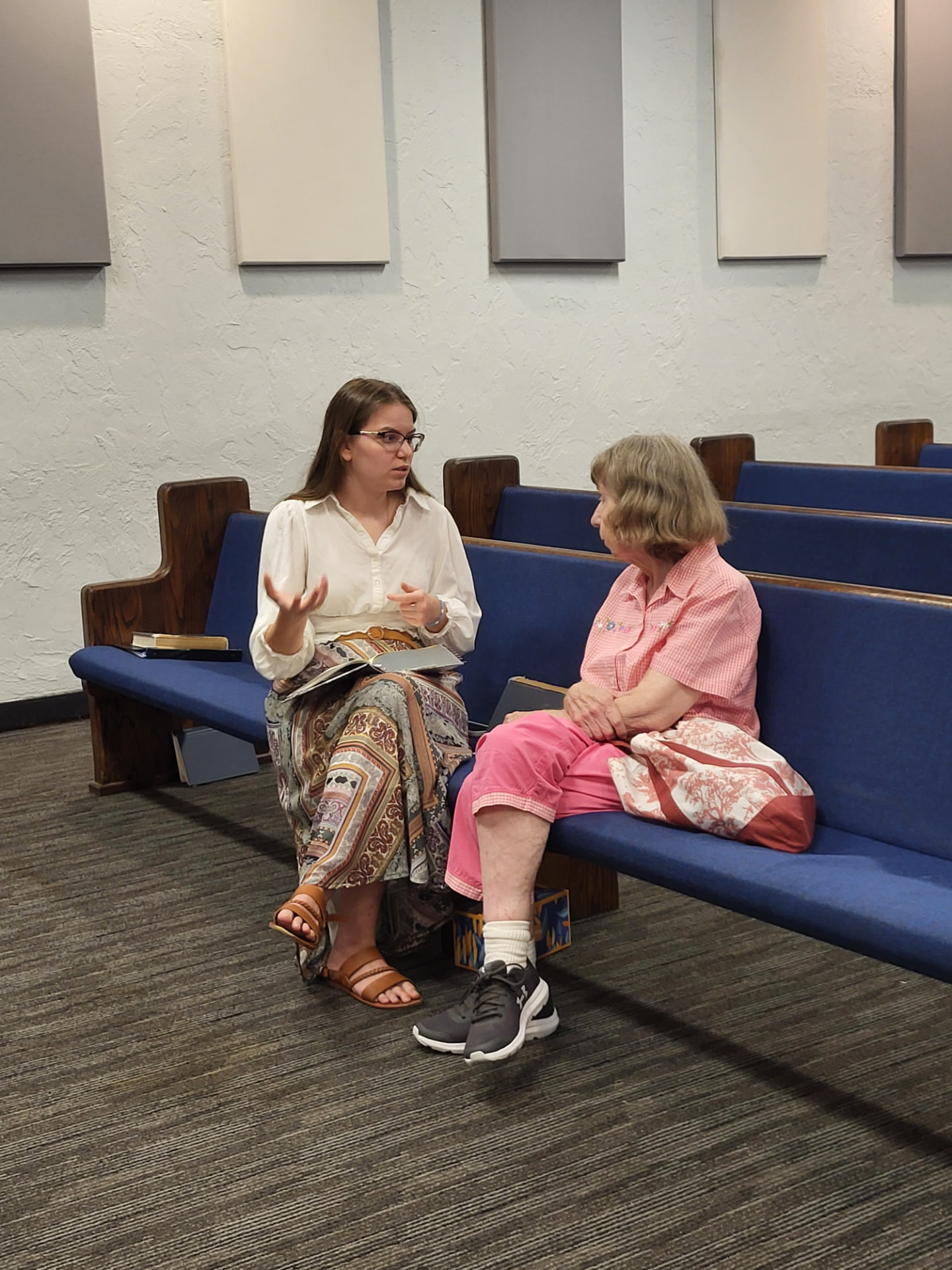 Two church members talking together in the pews with open Bibles