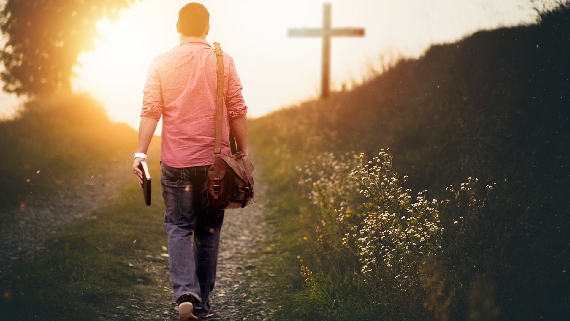 Man walking toward a cross at sunset