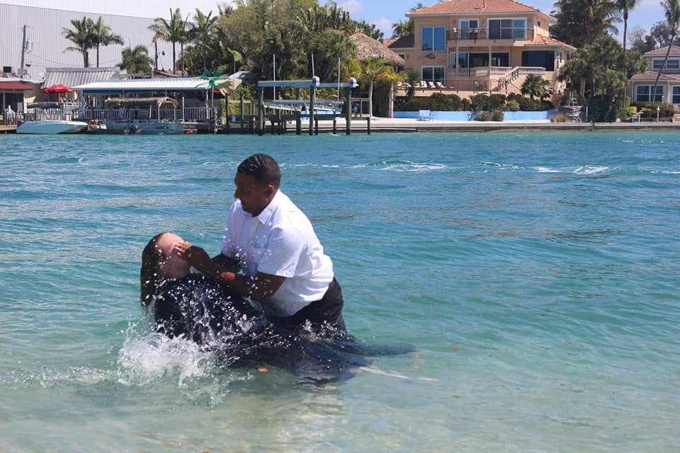 Outdoor baptism in the water surrounded by church family