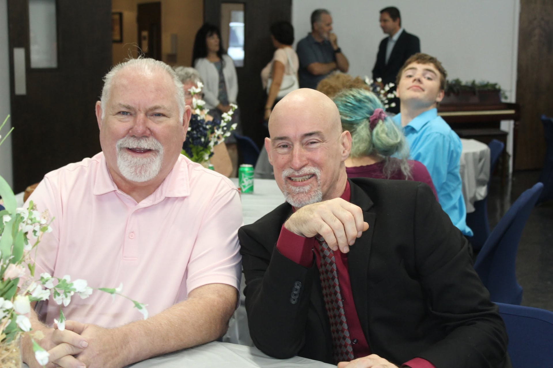 Two men from the church family smiling together at a fellowship meal